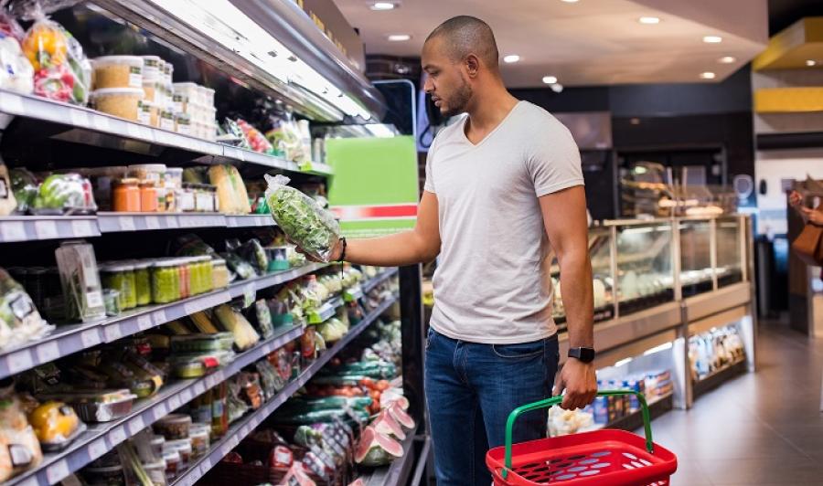 Young Black man reading food label at grocery store