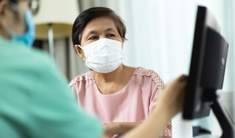 Doctor and older female patient in medical office looking at computer monitor