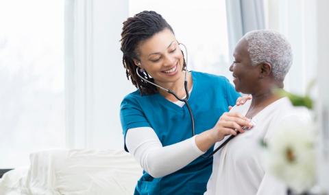 Young Black doctor attends to elderly Black woman