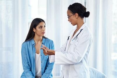 A doctor in an office explaining to a woman why cervical cancer screening is important