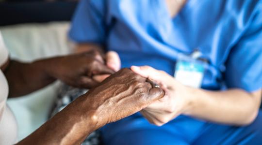 Nurse holding hands of elder Black woman