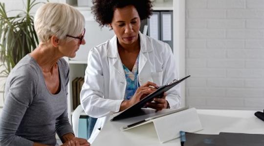 A doctor in an office explaining to a woman what common cervical cancer risk factors are