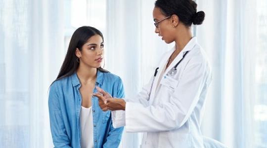 A doctor in an office explaining to a woman why cervical cancer screening is important