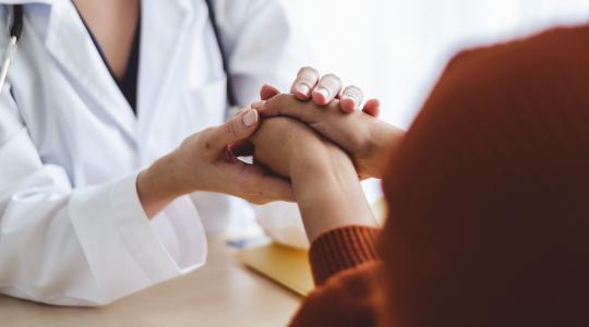 Female doctor holds hands and comforts patient